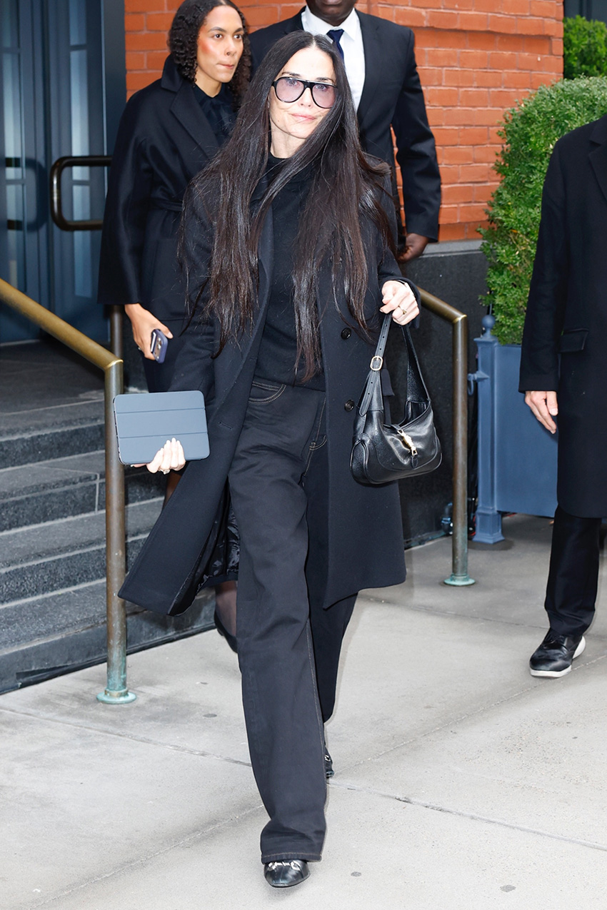 Demi Moore wearing a black coat, sweater, and jeans with Gucci shoes and the Gucci Jackie Slim Shoulder Bag