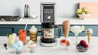 Ninja Creamie ice cream maker with a variety of frozen desserts surrounding it, all on a kitchen counter.