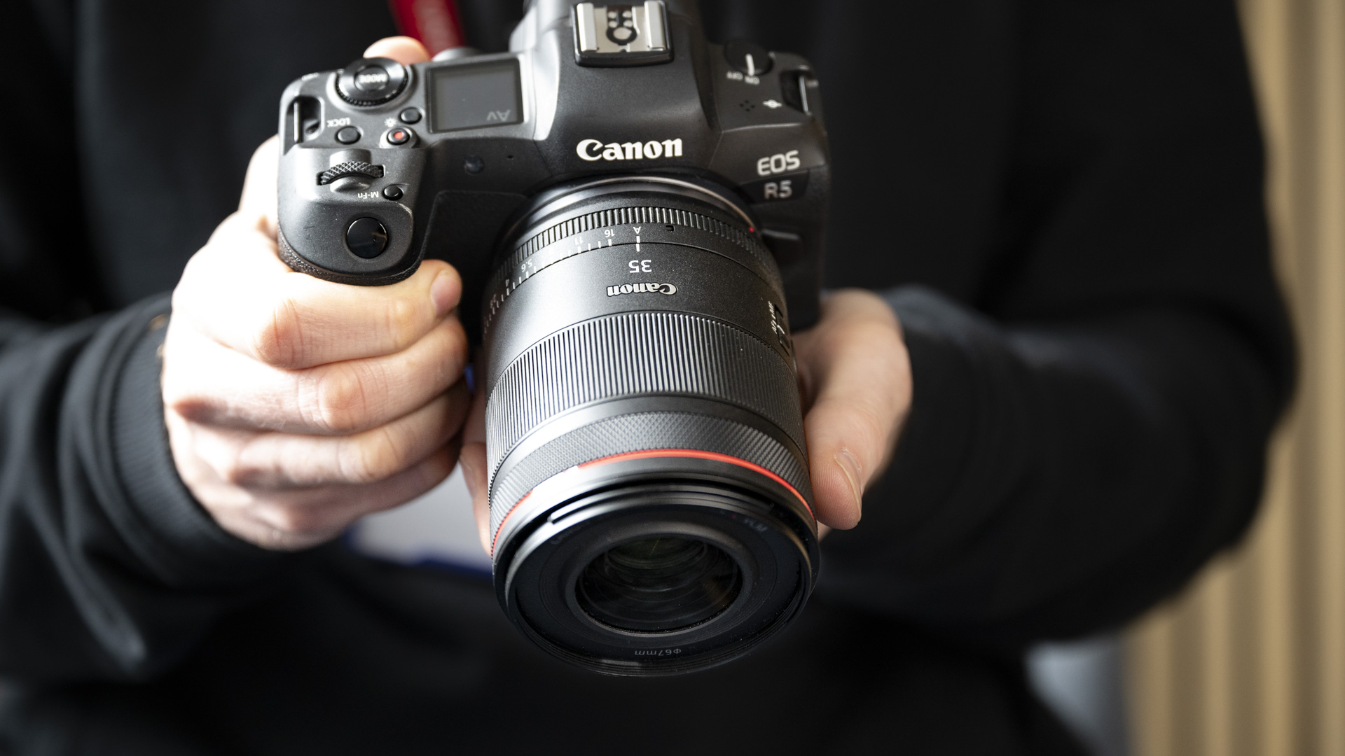 The Canon RF 35mm F1.4 lens attached to a Canon EOS R5, in the hand