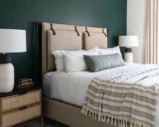 Modern bedroom with forest green wall and beige headboard with white lamps