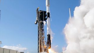 a black and white rocket launches from into a blue sky