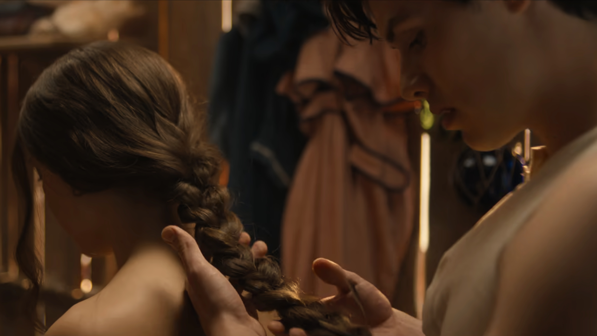 Enola (Millie Bobby Brown) has her hair braided by Lord Tewkesbury (Louis Partridge) in Enola Holmes 3.