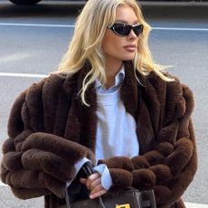 Elsa Hosk wears beige cord trousers with a fur-trimmed coat and a white zip-up hoodie.