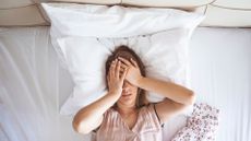 Young woman lies in bed with sleep problems caused by choosing a memory foam hybrid instead of a latex hybrid