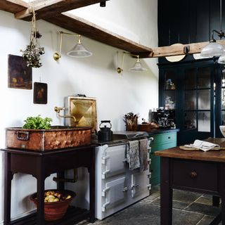 freestanding kitchen with white walls and white aga and copper sink on table and blue cabinet