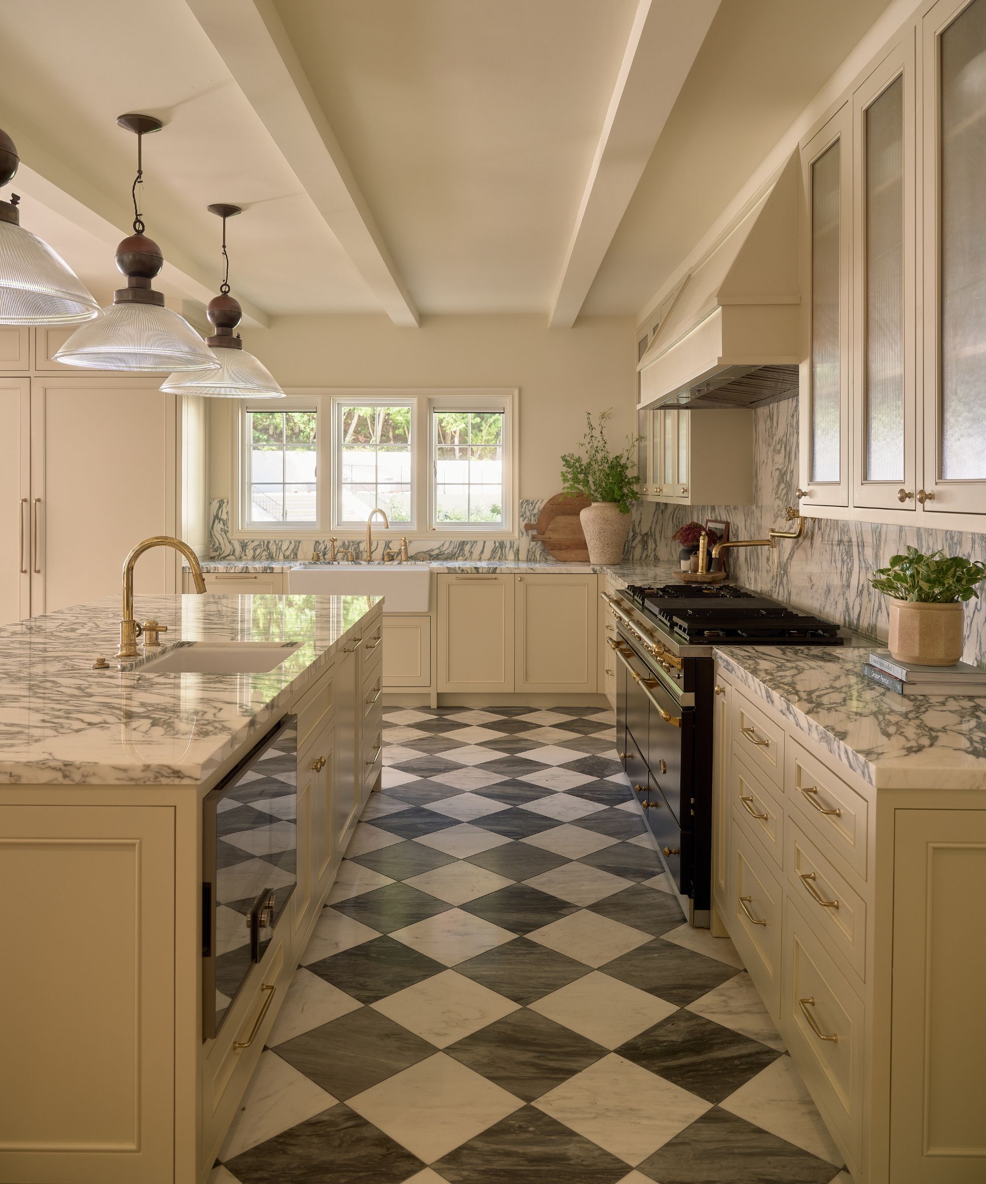 a large warm neutral kitchen with painted ceiling beams and a checkerboard floor