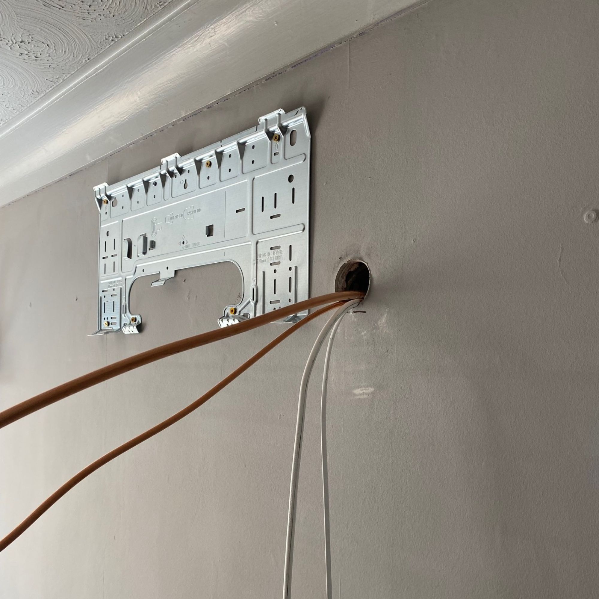 Wall bracket fitted to the wall and the pipework and cabling is fed through the wall to connect the indoor and outdoor air con units