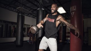 Man performs one-handed kettlebell swing in gym