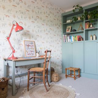 country cottage children's playroom with desk, chair and red lamp, bookshelves rug and cute wallpaper