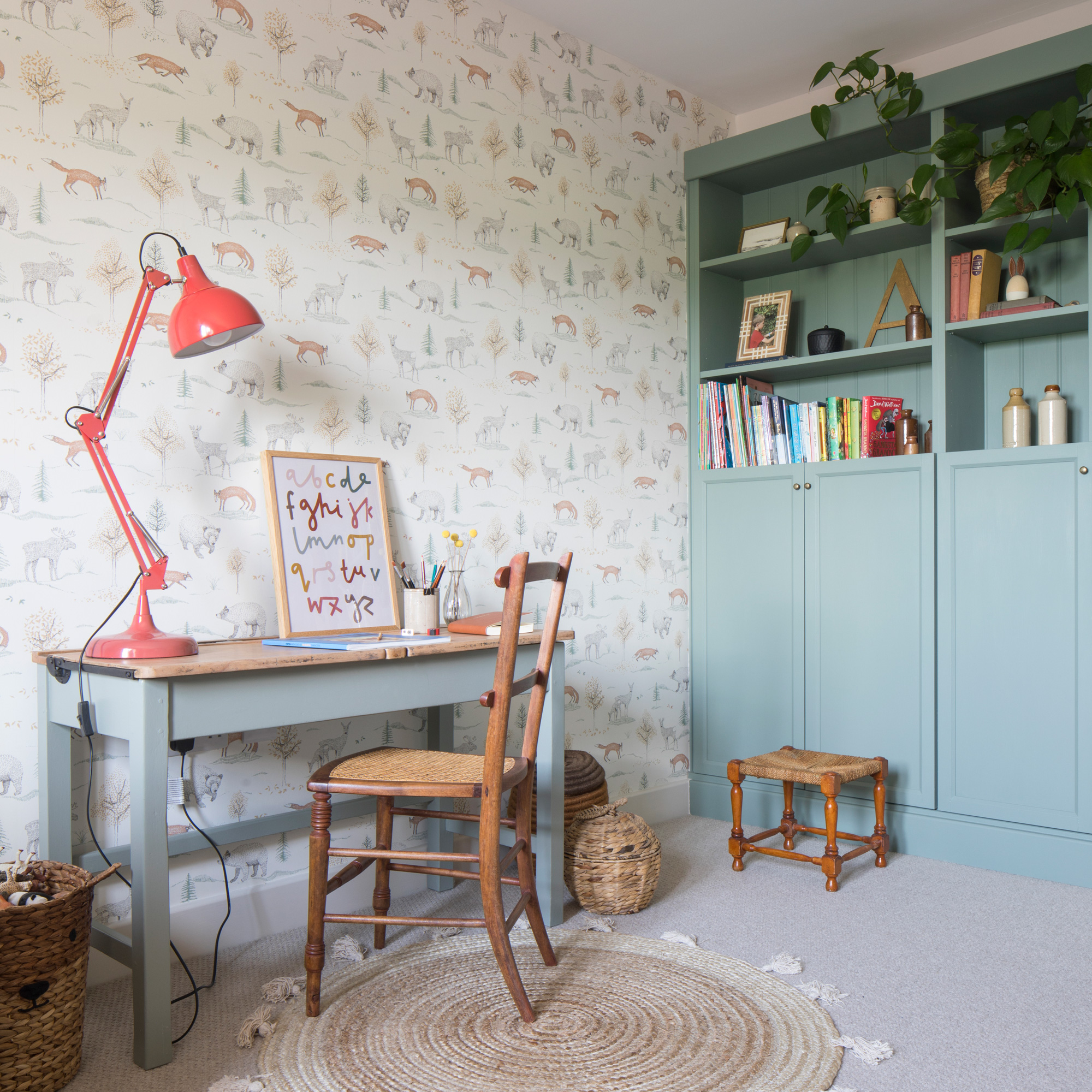 country cottage children's playroom with desk, chair and red lamp, bookshelves rug and cute wallpaper