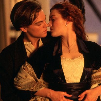 leonardo dicaprio as jack embracing kate winslet as rose from behind on the head of a ship in a still from the movie titanic
