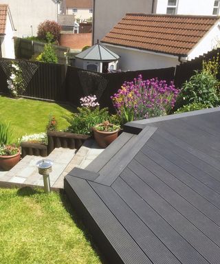 Dark grey compsoite decking with sloped stairs and planter decor in back garden