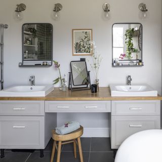 bathroom vanity unit with two sinks and mirrors on the wall