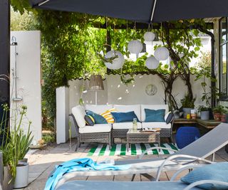 large patio with a patio umbrella and plant-covered pergola for shade