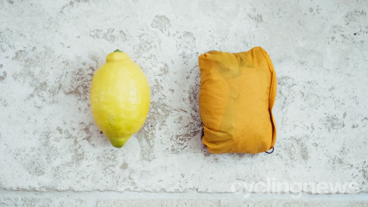 A gilet stuffed into its stuff sack next to a lemon