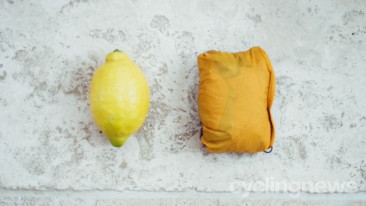 A gilet stuffed into its stuff sack next to a lemon