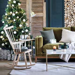 blue living room with Christmas tree wooden rocking chair and green velvet sofa