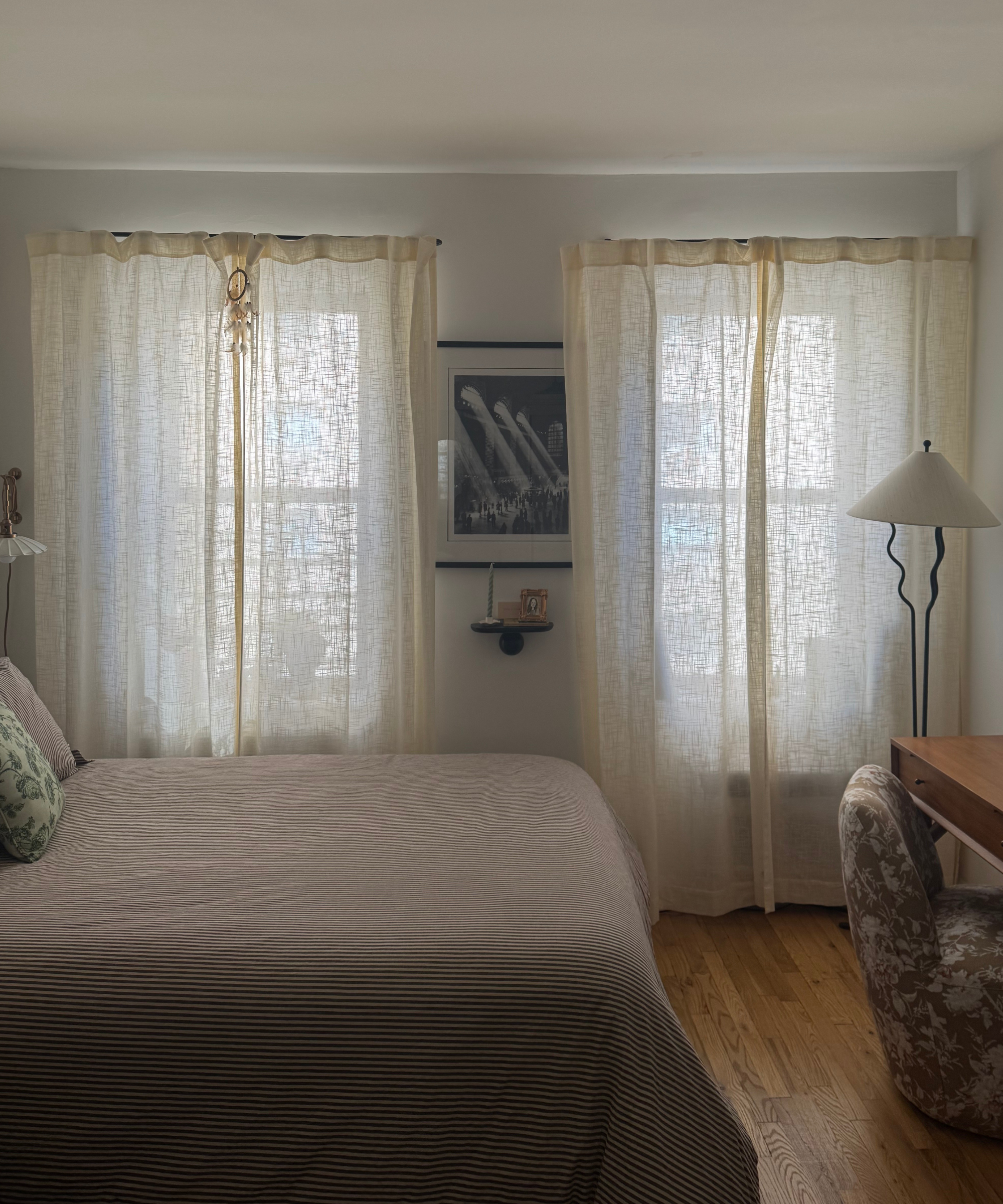a bedroom with sheer curtains in front of the windows