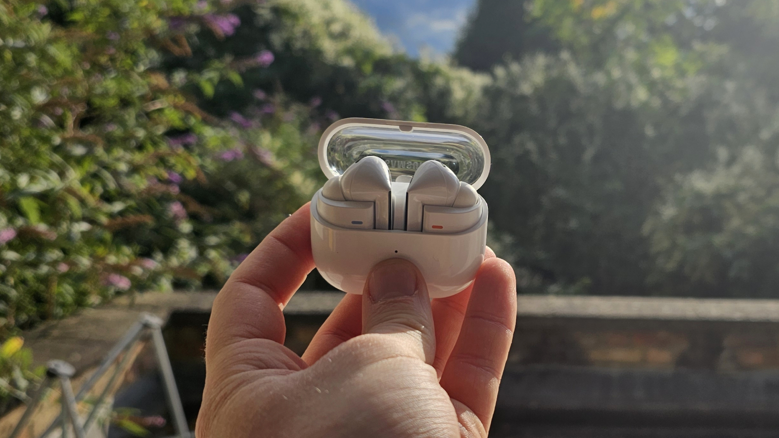The Samsung Galaxy Buds 3 Pro against a leafy background.