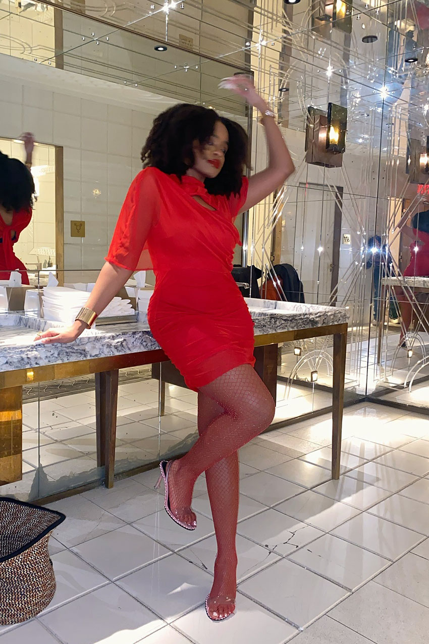 A woman wearing a red dress, red stockings, and heels