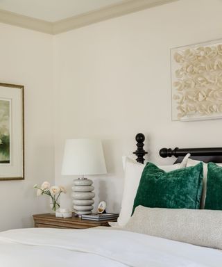 calming bedroom with white walls, white bedding and green accent pillows