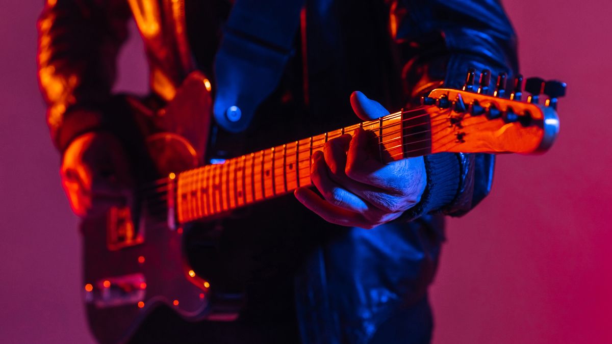 Close-up of a guitarist playing the guitar, macro. Man&#039;s hand on the fretboard with strings