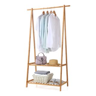 A bamboo coat rack with shirts and shelves on it