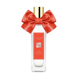 A product shot of the Jo Malone London Fir & Artemisia Cologne, which features an orange bow on the bottle, on a white background