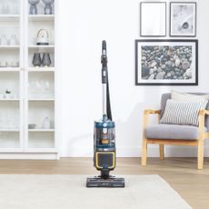 Cordless upright vacuum cleaner placed in the middle of living room