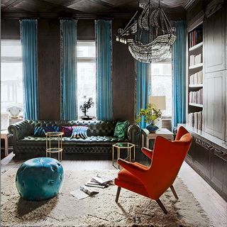living room with cosy carpet on floor and ghost-ship-style chandelier with orange wingback chair
