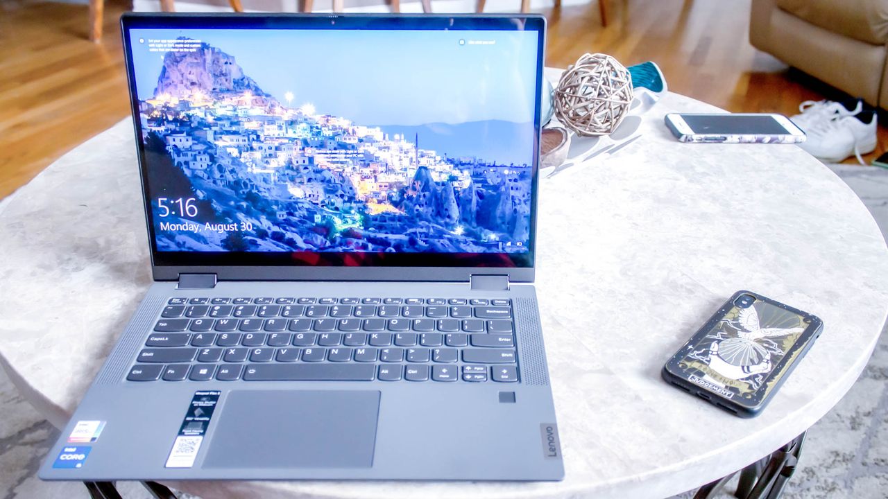 An open and powered on laptop sits on top of a white marble table