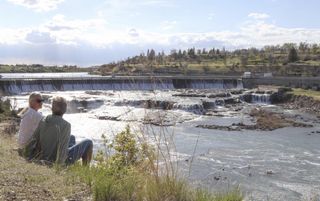 Mature couple watch look down river flowing from dam in Great Falls MT