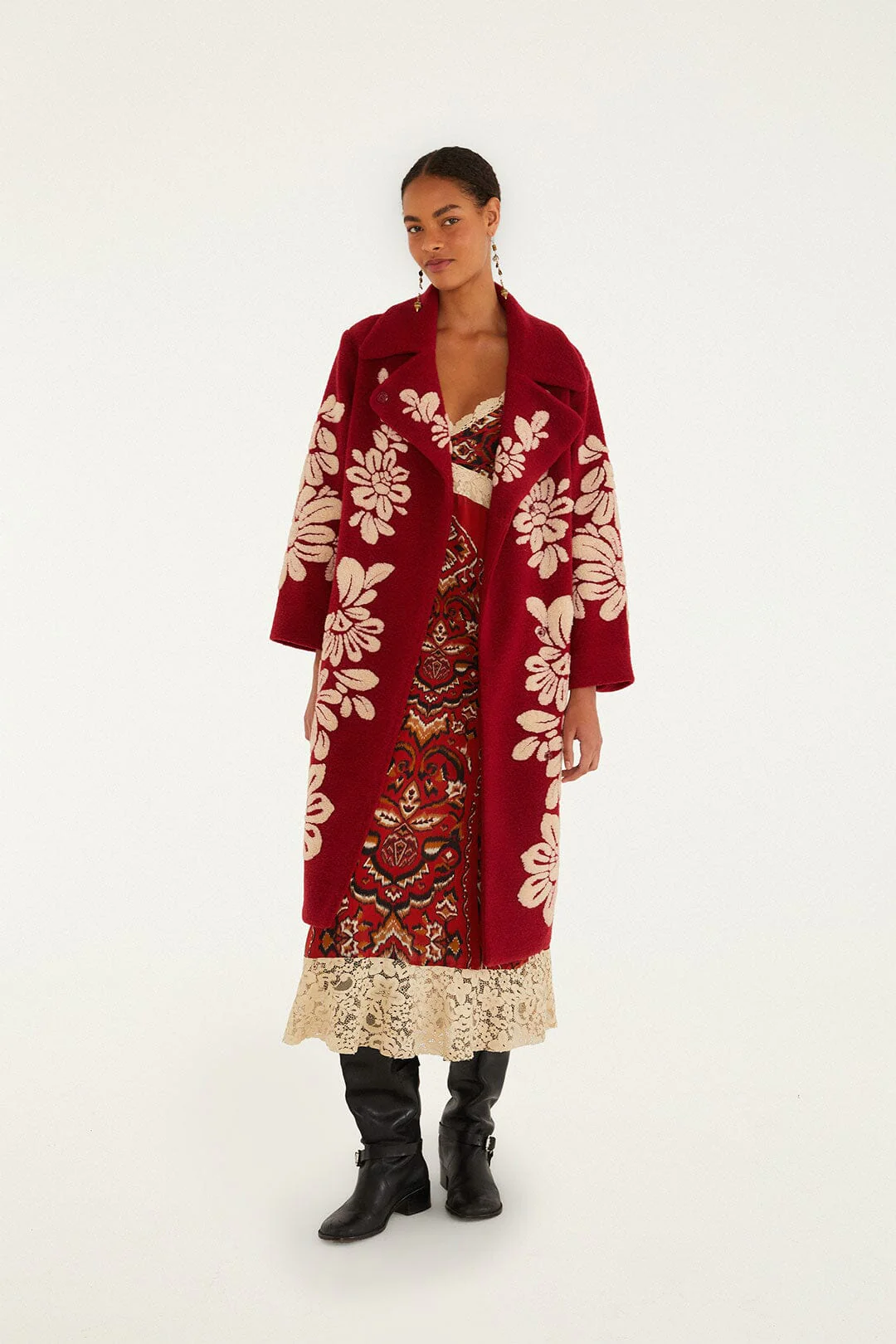 A model wearing a burgundy coat adorned with cream floral motifs.