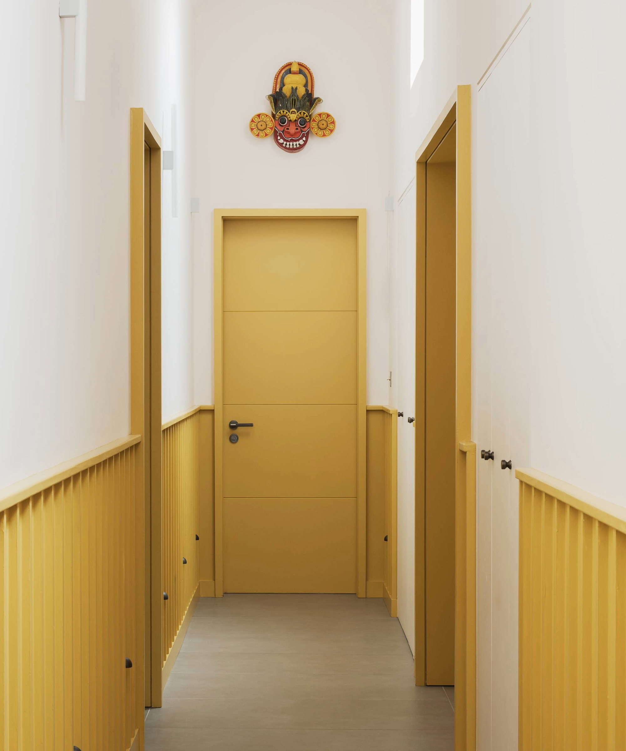 Hallway with yellow doors and lower paneling 