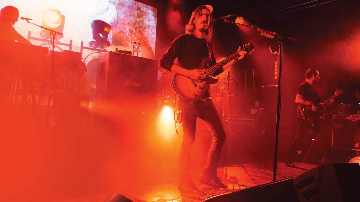 Opeth&#039;s Mikael Akerfeldt on stage bathed in orange light