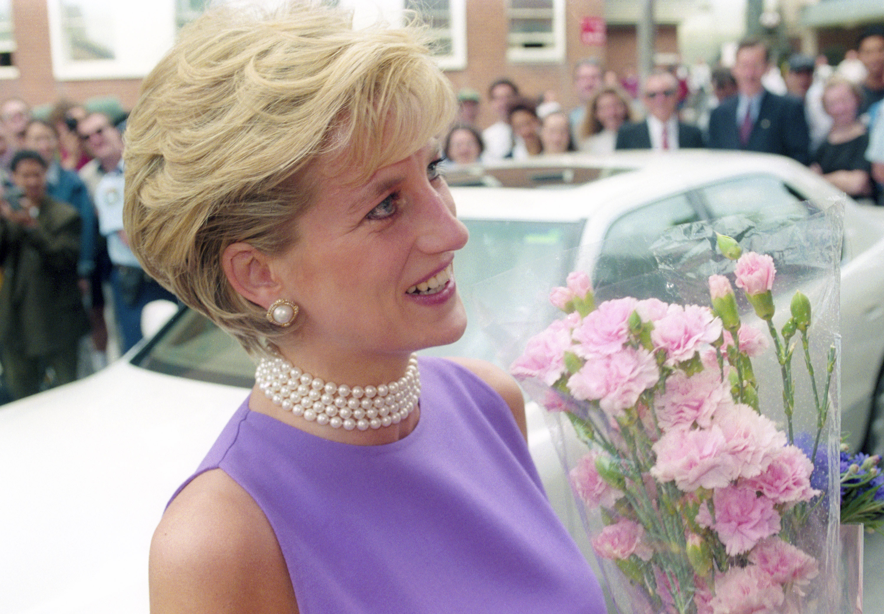 Princess Diana wearing a purple dress and holding flowers