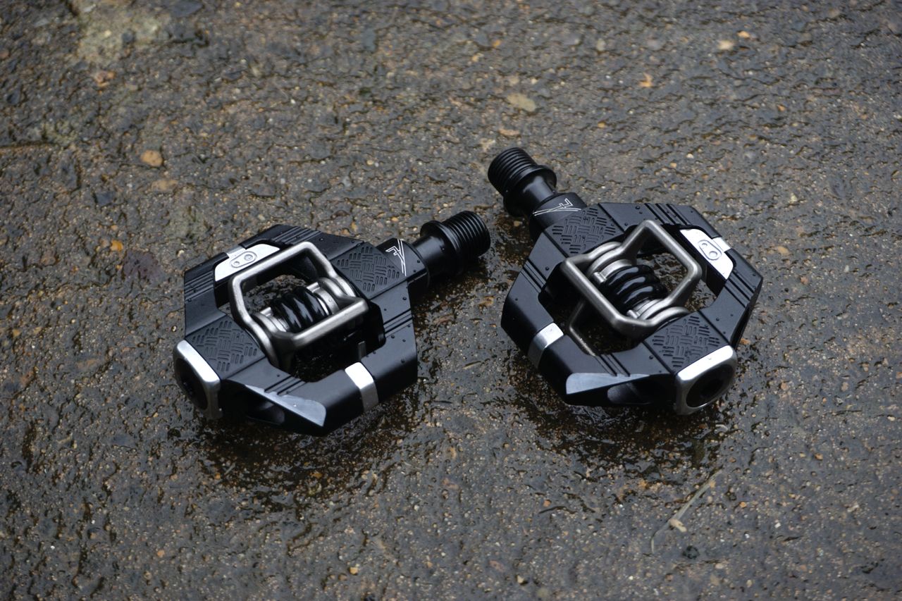 A pair of black gravel bike pedals on tarmac