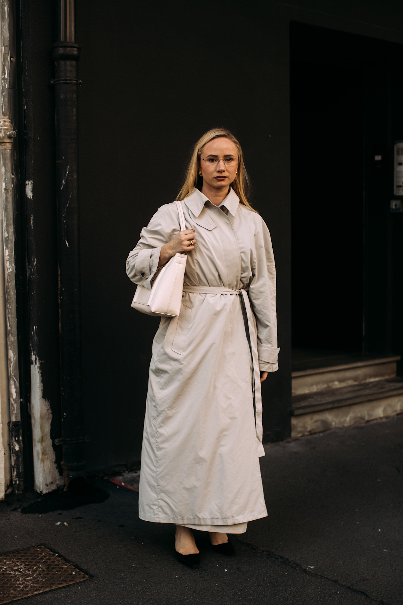 fashion week attendee wears trench coat and black flats