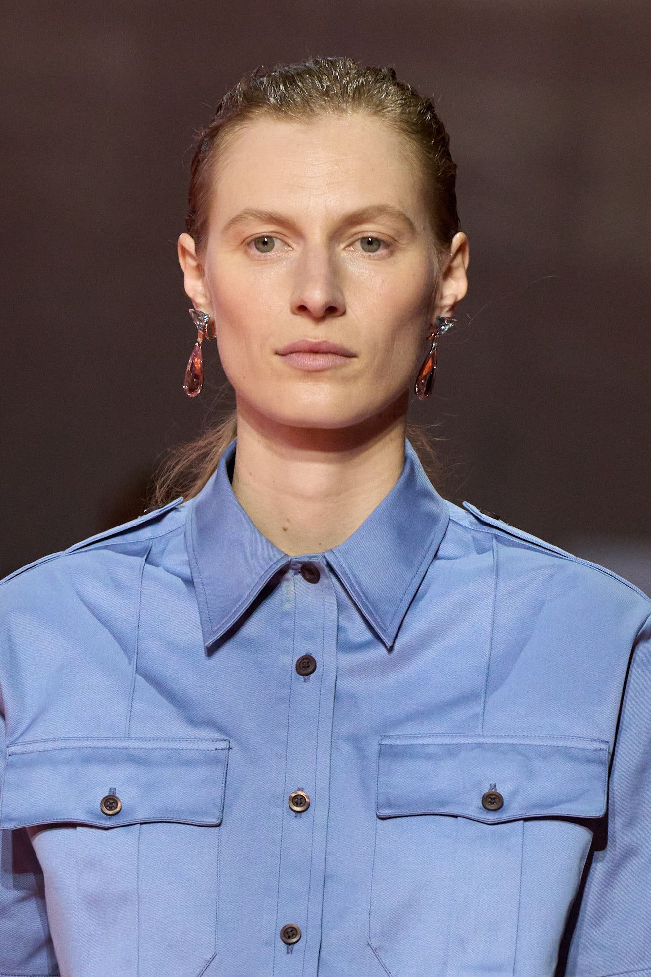 A model at the SS26 Prada show wearing a blue shirt with a wet-look hairstyle