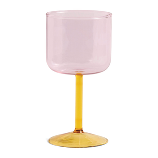 A wine glass with a pink body and orange stem