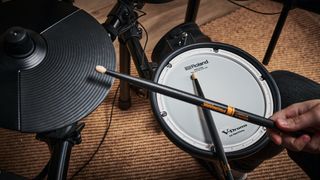 Close up of drumsticks over an electronic drum set hi-hat and snare drum pad