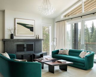 Living room with two teal sofas facing across coffee table and concealed TV in mantel