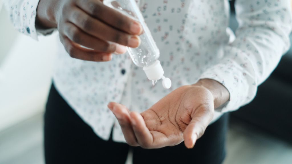 person applying hand sanitizer from clear bottle