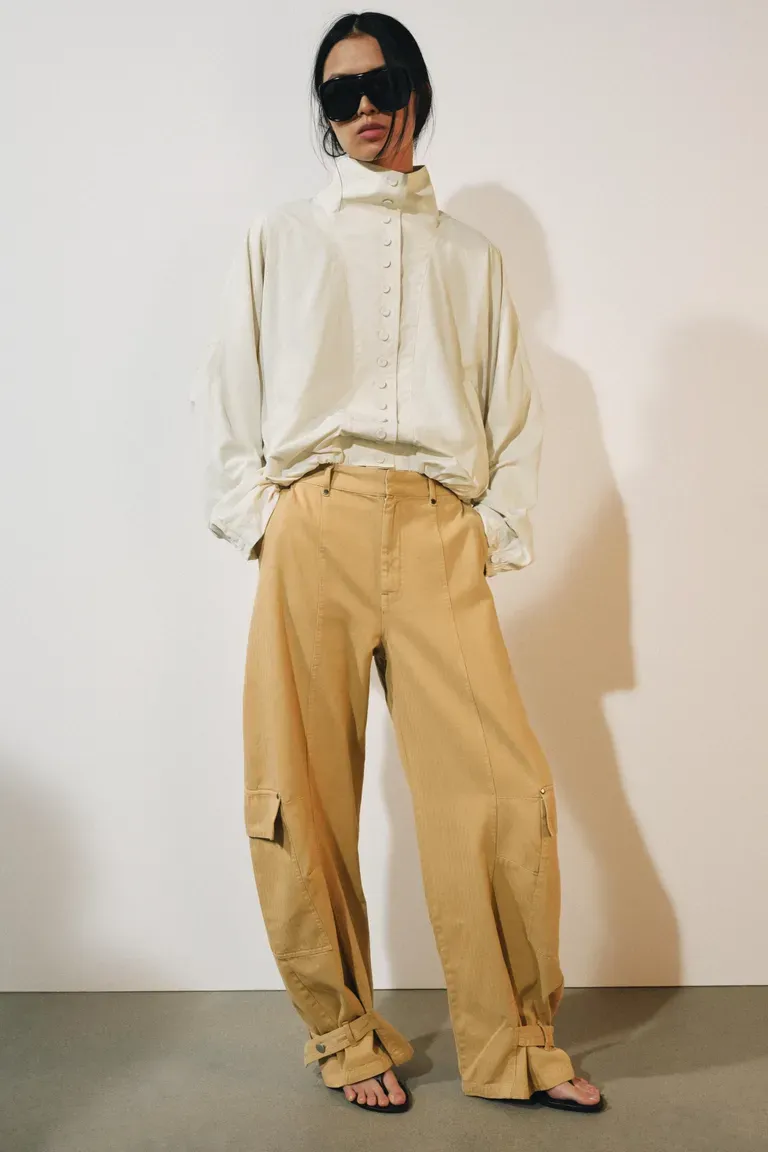 Woman wears white Zara windbreaker, camel trousers and sandals