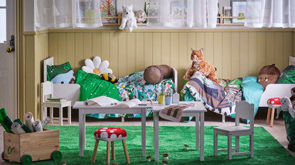 A display of the SKOGSDUVA collection, Featuring mushroom toadstool stool covers, table and chairs, green grass style rug, bed with nature themed bedding and cuddly toys