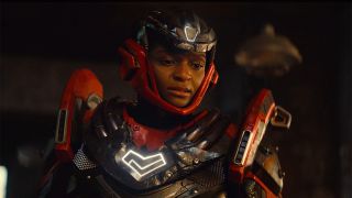 An unmasked Riri Williams wearing her new red and black armored suit in Ironheart episode 6