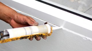 Person using caulking gun to caulk window