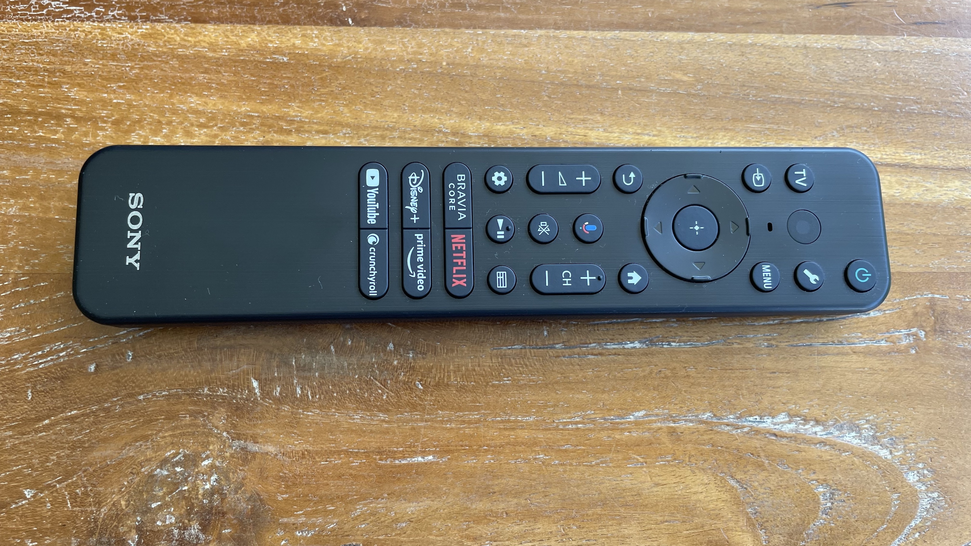 The Sony XR-65A80L remote control on a wooden surface