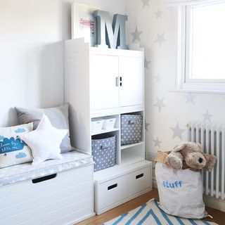 childrens room with white cupboard and wooden flooring