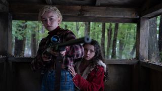 Charlotte (Julia Garner) protects Ginger (Matilda) with a rifle in Wolf Man 